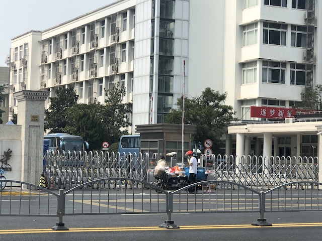上海・封鎖される大学の門でデリバリーした商品を受け取る学生